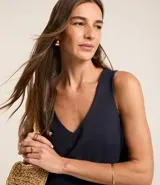 Musculosa en piquet color verde oliva, con escote en pico, breteles anchos, pequeñas aberturas laterales y bajos con pespuntes.