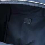 Mochila azul de poliéster con acceso trasero con cierre, correa regulable para usar como mochila o bandolera, herrajes plateados, un compartimento principal, un bolsillo interno con cierre, tres bolsillos externos con cierre y un bolsillo externo abierto.