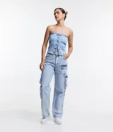 Pantalón recto de jeans celeste con cintura alta, bolsillos cargo laterales y detalle de aro metálico en la pierna.