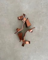 Sandalias plateadas con tira delantera, tobillera con hebilla y taco geométrico.