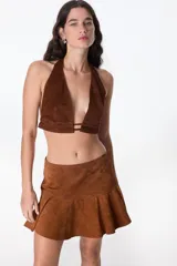 Top corto marrón de cuero con escote halter y espalda descubierta.