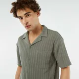 Camisa verde de manga corta con tejido calado, cuello clásico y bolsillo en el pecho.