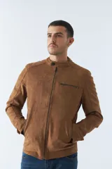 Campera de gamuza color beige con cuello mao, cierre frontal con cremallera, bolsillos laterales con cierre y puños con botón.