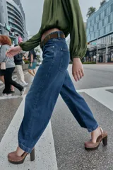 Jeans de tiro alto con pernera ancha y corte cropped. Presenta diseño de cinco bolsillos, cierre frontal con cremallera y botón, e incluye un cinturón a juego.