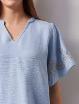 Blusa color beige de crepe, marca Batía, con cuello a la base y escote en V. Manga corta amplia con bordados.