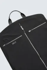 Portatrajes negro confeccionado en tejido técnico. Cuenta con un compartimento principal con cierre mediante cremallera, dos bolsillos auxiliares con cierre mediante cremallera y asas de mano fabricadas en piel.