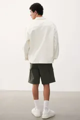 Short cargo color verde militar, de corte regular, con cintura elástica ajustable con cordón, bolsillos laterales, bolsillos cargo con solapa y cierre autoadherente en las piernas y bolsillos traseros con solapa y cierre autoadherente.