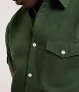 Camisa de hombre de manga corta en lino color blanco, con cuello clásico, botonadura frontal y bolsillo de parche en el pecho. Corte recto.