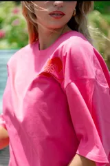 Remerón oversize color fucsia con estampado de dos manos formando un corazón en el pecho y la frase "conecta contigo primero".