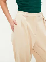 Pantalón gris oscuro de corte amplio, con pinzas en la cintura y bolsillos laterales.