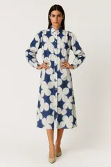 Vestido camisero midi con estampado de flores grandes en azul y blanco, manga larga abullonada, cuello camisero y cierre frontal con botones.