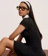 Vestido corto negro de corte evasé, con escote cuadrado y breteles anchos. Presenta costuras verticales en el frente y la espalda para definir la silueta.