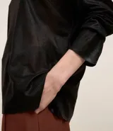 Blusa negra de punto liviano con escote redondo, manga larga y sisa raglán. Tiene una malla con lámina metálica.