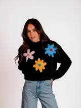 Sweater negro de tejido bouclé con cuello redondo y mangas largas. Presenta apliques de flores tejidas de colores en el frente.