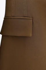 Blazer marrón de corte entallado, con cuello solapa, manga larga, bolsillos delanteros con solapa y cierre frontal con un botón.