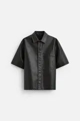 Sobrecamisa negra de manga corta confeccionada en tejido efecto piel, con cuello solapa, bolsillo frontal de parche y cierre frontal con botonadura oculta.
