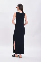 Vestido largo de punto negro con cuello redondo y sin mangas. Tiene corte recto y aberturas laterales en el ruedo.