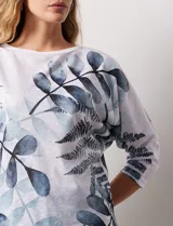 Buzo blanco con estampado de hojas en tonos azulados, de cuello redondo y mangas 3/4.