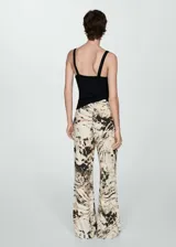 Pantalón wideleg con estampado animal print en tonos beige, marrón y negro. Tiene tiro medio y cierre de cremallera invisible en el lateral.