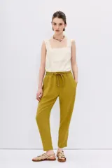 Pantalón babucha de tiro alto confeccionado en símil lino color verde oliva. Tiene calce relajado que ajusta hacia el ruedo y largo hasta los tobillos, la cintura es elastizada y cuenta con 6 presillas y lazo de ajuste en la misma tela. Tiene bolsillos diagonales en laterales y dos bolsillos ojal falsos en espalda.