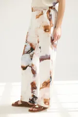 Pantalón de lino color blanco con estampado abstracto en tonos celeste, marrón y violeta.