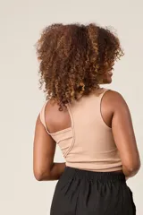 Top color beige de punto acanalado, con diseño asimétrico de un solo hombro y corte corto.