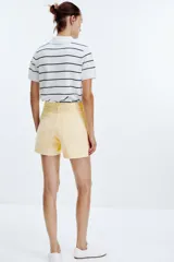Shorts de jean celeste con tiro alto, cinco bolsillos y cierre frontal cruzado con cremallera y botones.