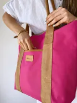 Bolso tipo tote color fucsia con manijas y detalles en cuero color marrón.