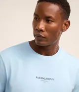 Remera celeste de algodón, corte clásico, con cuello redondo y mangas cortas. Estampa lettering Sailing&Wind en el pecho.