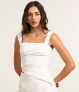 Blusa blanca de bengalina con breteles anchos y escote cuadrado. Presenta fruncido lateral y bajo asimétrico.