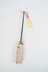 Paraguas plegable de color beige claro con la palabra "hello." estampada en azul. Incluye un asa de mano tipo correa en tonos amarillo y rosado.