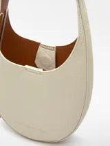 Bandolera pequeña color tostado, con textura granulada, un compartimento y cierre magnético. Tiene asa larga regulable y logo grabado.