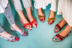 Bailarinas destalonadas celestes con bordado floral multicolor, tiras rojas con hebillas y suela de cuero.