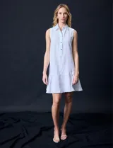 Vestido corto blanco de gasa, sin mangas, con cuello camisero, abertura central con botones y terminación de ruedo con volado.