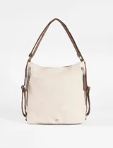 Cartera convertible en mochila color natural, con correa de hombro marrón y detalles de cierres metálicos.