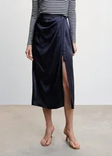 Falda midi cruzada color celeste, de tejido satinado y fluido, con abertura lateral, cierre lateral de cremallera, tiro medio, detalle fruncido y cierre de lazo lateral.
