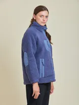 Campera de sherpa color negro con cierre frontal con botones a presión y bolsillos laterales.