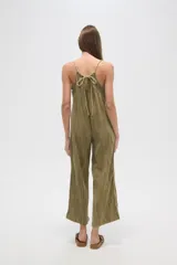 Mono de algodón negro, estilo lencero, con tirantes finos, escote en V y bolsillos frontales. El calce es holgado y presenta un cordón ajustable en la cintura.