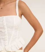 Blusa corset de laise blanca con bordado de flores, escote cuadrado, breteles y volados en el ruedo. Cierre frontal con corchetes.