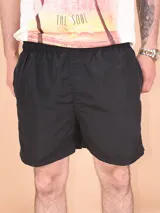 Short negro liso, de corte deportivo y largo por encima de la rodilla, con cintura elástica.