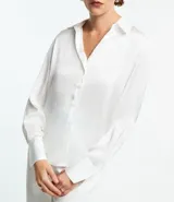 Camisa blanca de satén con cuello inglés, manga larga y cierre frontal con botones.