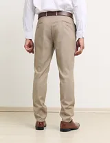 Traje de vestir color tostado, compuesto por saco con solapa de muesca, cierre de dos botones, bolsillos con solapa y pantalón de corte recto.