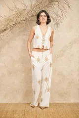 Pantalón de lino color crudo con bordados dorados, corte palazzo y cintura alta.