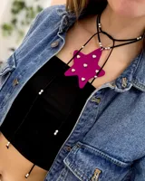 Gargantilla tipo choker con dije de estrella fucsia de acrílico con strass, y tiras de cuero ecológico negro con cuentas plateadas.
