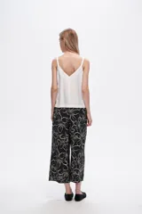 Pantalón capri negro con estampado floral en color crema, de corte ancho y tiro alto.