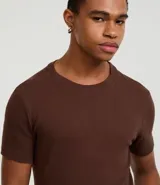 Remera muscle de manga corta confeccionada en media malla color crudo, sin estampa, con cuello redondo.