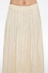 Falda midi de corte línea A con vuelo, confeccionada en poliéster. Presenta un estampado abstracto en tonos tierra, beige, marrón y verde musgo. Tiene cremallera lateral invisible y pliegues irregulares cosidos en la cintura.