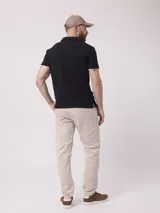 Chomba negra lisa de poliéster, algodón y core spun yarn, con cuello clásico y mangas cortas.