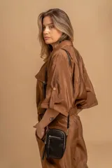 Bandolera compacta de símil cuero color rojo, con correa regulable y desmontable. Posee apertura superior, bolsillo frontal con cierre y bolsillo trasero abierto.