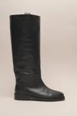 Bota alta de cuero color marrón, con caña recta y suela plana.